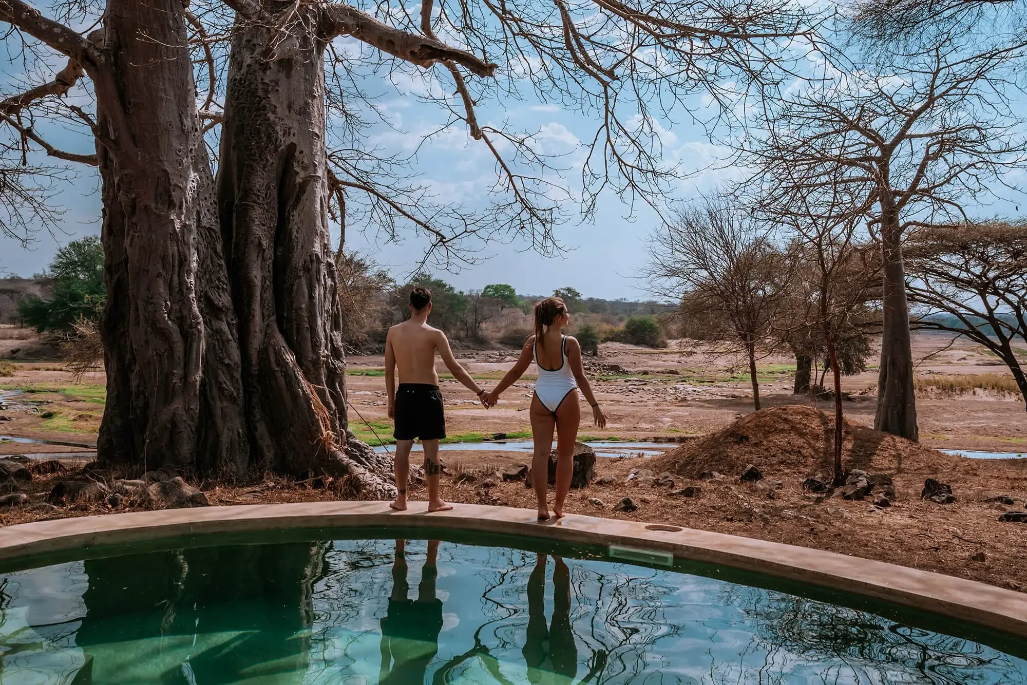 Couple enjoying a private plunge pool at a luxury safari lodge in Tanzania surrounded by iconic baobab trees.