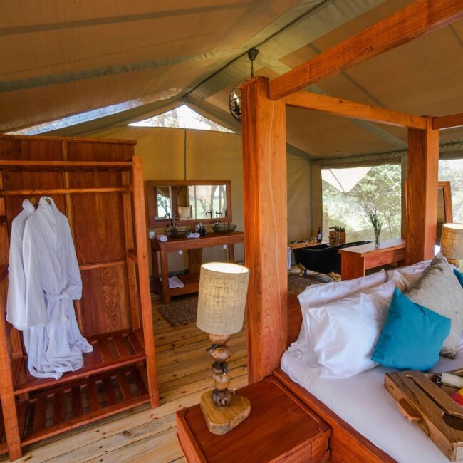 Interior of a luxury safari tent with bed, robes, washstand and bathtub in the Serengeti, Tanzania