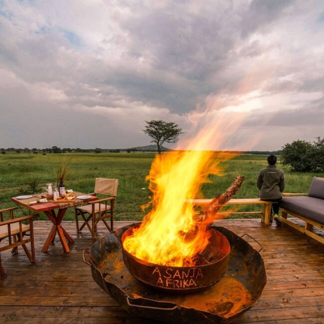 Fireside dining deck overlooking the green Serengeti plains at dusk, Tanzania