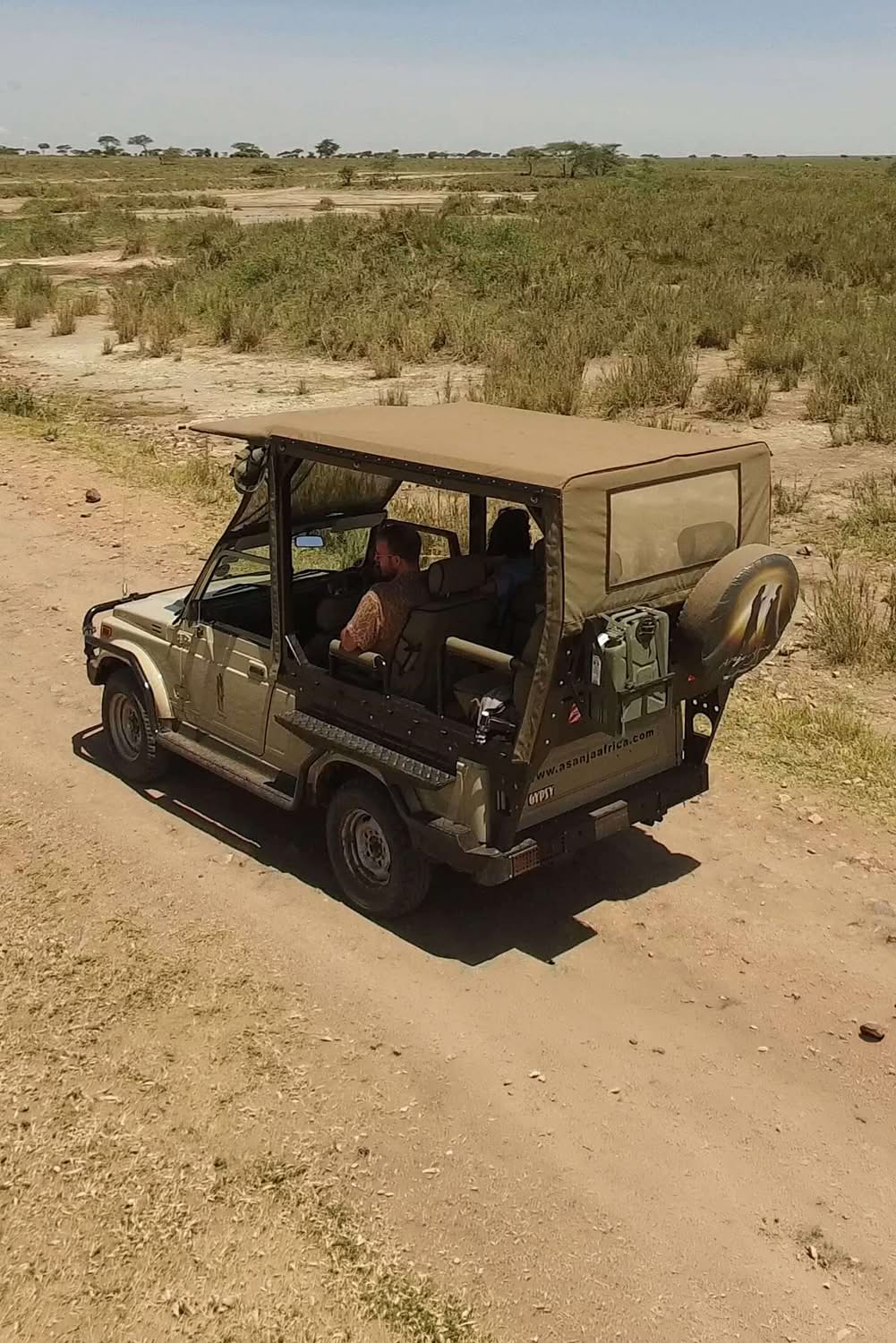 Safari vehicle on a game drive across the open Serengeti plains, Tanzania